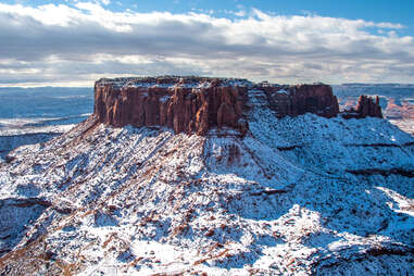 a large rock mesa in the middle of a snow-covered canyon