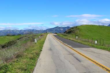a road leading through grassy hills