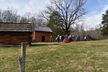 a tour group walking past historic cabins