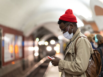 Man waits for subway in a mask