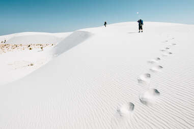 people walking across sandy dunes