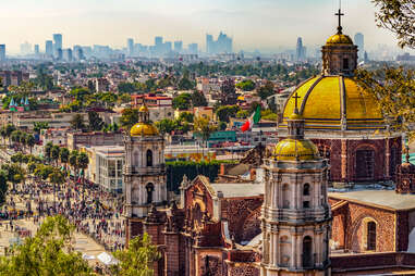 Basilica of Our Lady of Guadalupe. Cupolas of the old basilica and cityscape of Mexico City on the far horizon