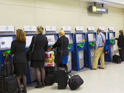 people lined up at Global Entry kiosks in an airport