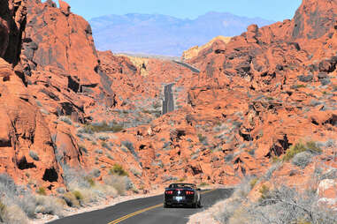 car driving through a red rock canyon toward mountains