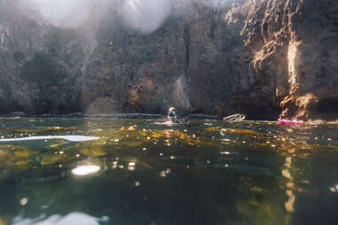 20 something man in dive gear next to his red kayak at Santa Cruz Islands in Channel Islands National Park.