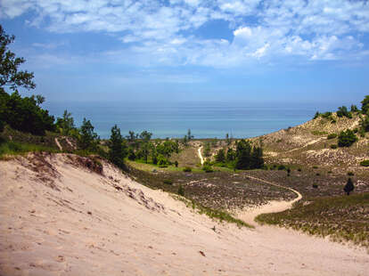 a sandy path leading to the edge of a lake