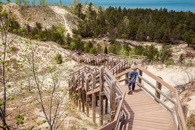 a person walking down a stairs boardwalk toward the beach