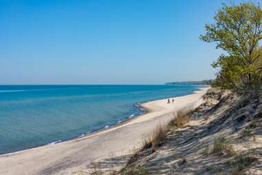 two people walking along a winding lakeshore