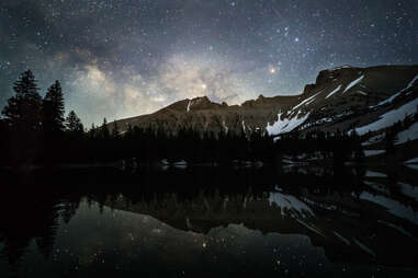 a mountain and lake beneath a starry sky 