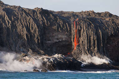 lava pouring over volcanic rock into the Pacific Ocean