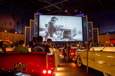 people in fake cars in a drive in diner restaurant