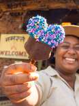 a woman holding a mickey mouse shaped popsiclee