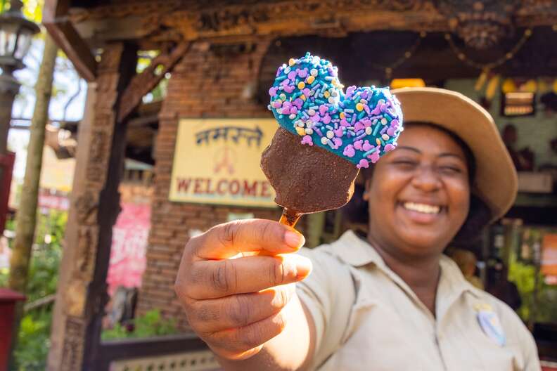 a woman holding a mickey mouse shaped popsiclee