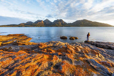 woman enjoys a sunset view in a seaside national park with mountains in the distance