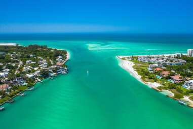 a crystal blue river leading out to the ocean between two islands