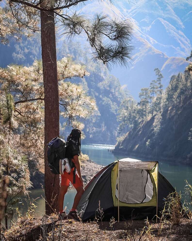 Person looking at a river next to a tent