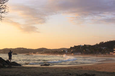 Man watching a sunset over Pacific Ocean and a hillside Mexican town