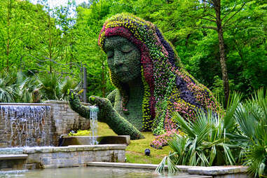 a giant woman made of flowers in a botanical garden