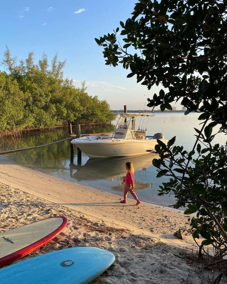 Girl on sandy beach in front of small boat