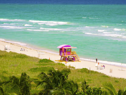 View from up high of pink and yellow wood lifeguard stand on white sand of Miami Beach