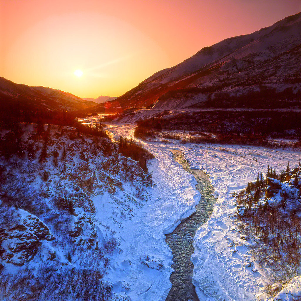 The sun rises over Nenana River behind mountains