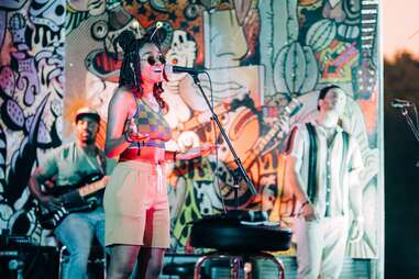 a performer and a band on stage at a cool venue