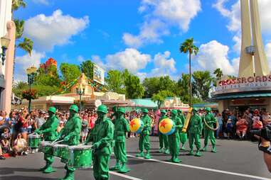 crowds surrounding actors dressed as little green soldiers at a Disney Parade on a sunny day