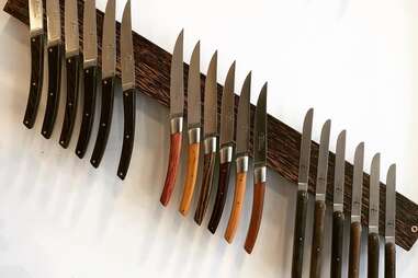 Man Sharpening His Pocket Knife with a Whetstone on a Rustic