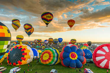hot air balloons on the ground and in the sky surrounded by crowds