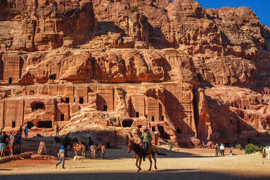 Facades of old rock houses against a blue sky with white clouds in ancient Petra in Jordan