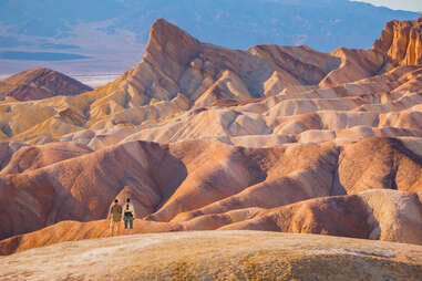 hikers standing in front of an enormous, winding desert landscape