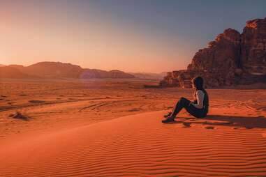 person sitting on the edge of a vast desert