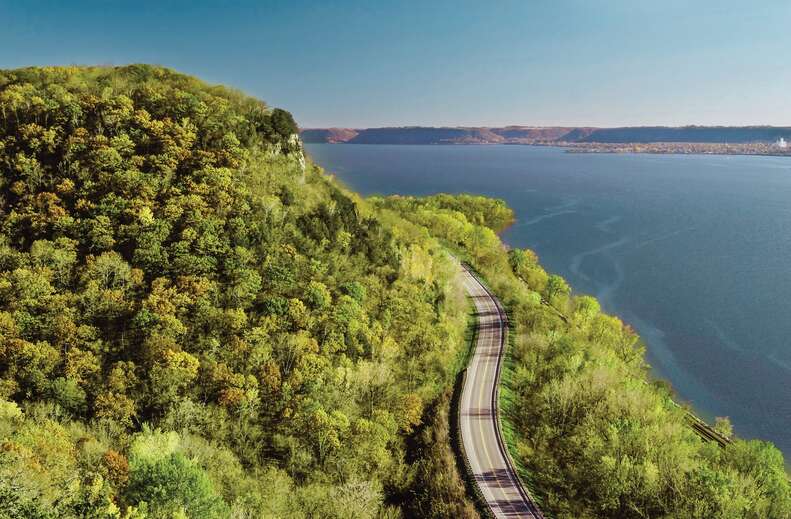 a highway winding between a mountain and lake