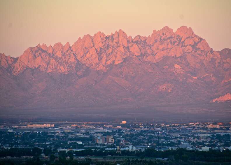 enormous craggy mountains over a cityscape