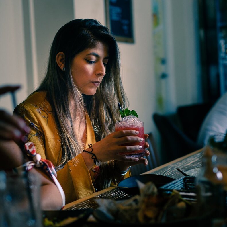 Woman drinking a purple cocktail