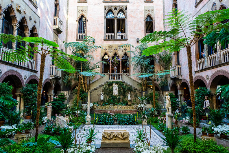 an inner courtyard of a historic home, with palm trees and greenery