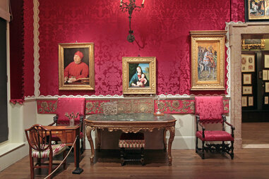 a room with brocade wallpaper and paintings with gold frames