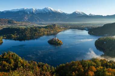 castle on an island in the middle of a lake surrounded by mountains and forests