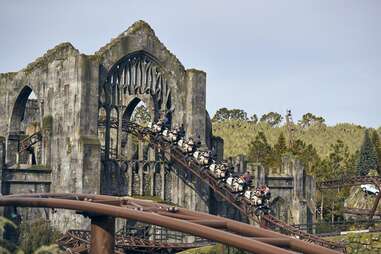 people on a rollercoaster that winds through castle ruins