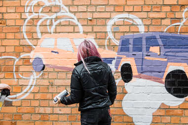 Woman painting mural on wall