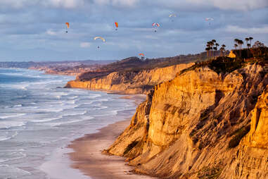 Paragliders floating over cliffs and beach