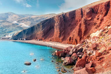 Red hillside by blue water