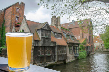 Glass of beer with view of historic houses and canal in Bruges