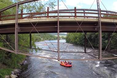 people in inner tubes floating down a tree lined river