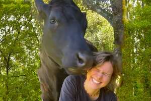 woman smiling next to her horse