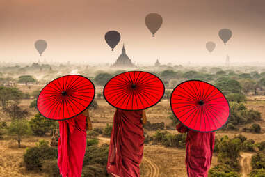 Back side of three Buddhist novice are walking over the Ancient Temples