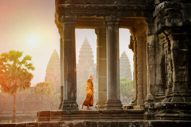 Monks walk on the balcony to see the stone carving at sunset of Angkor Wat