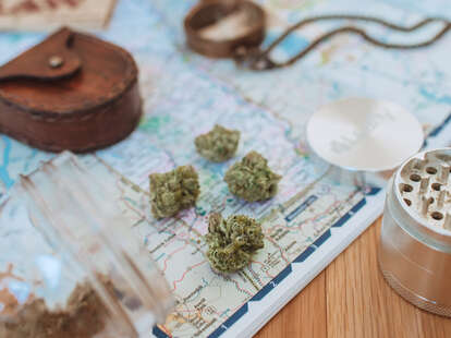 cannabis, compass, and other travel tools on top of a roadmap