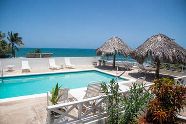 pool chairs around pool with ocean in background