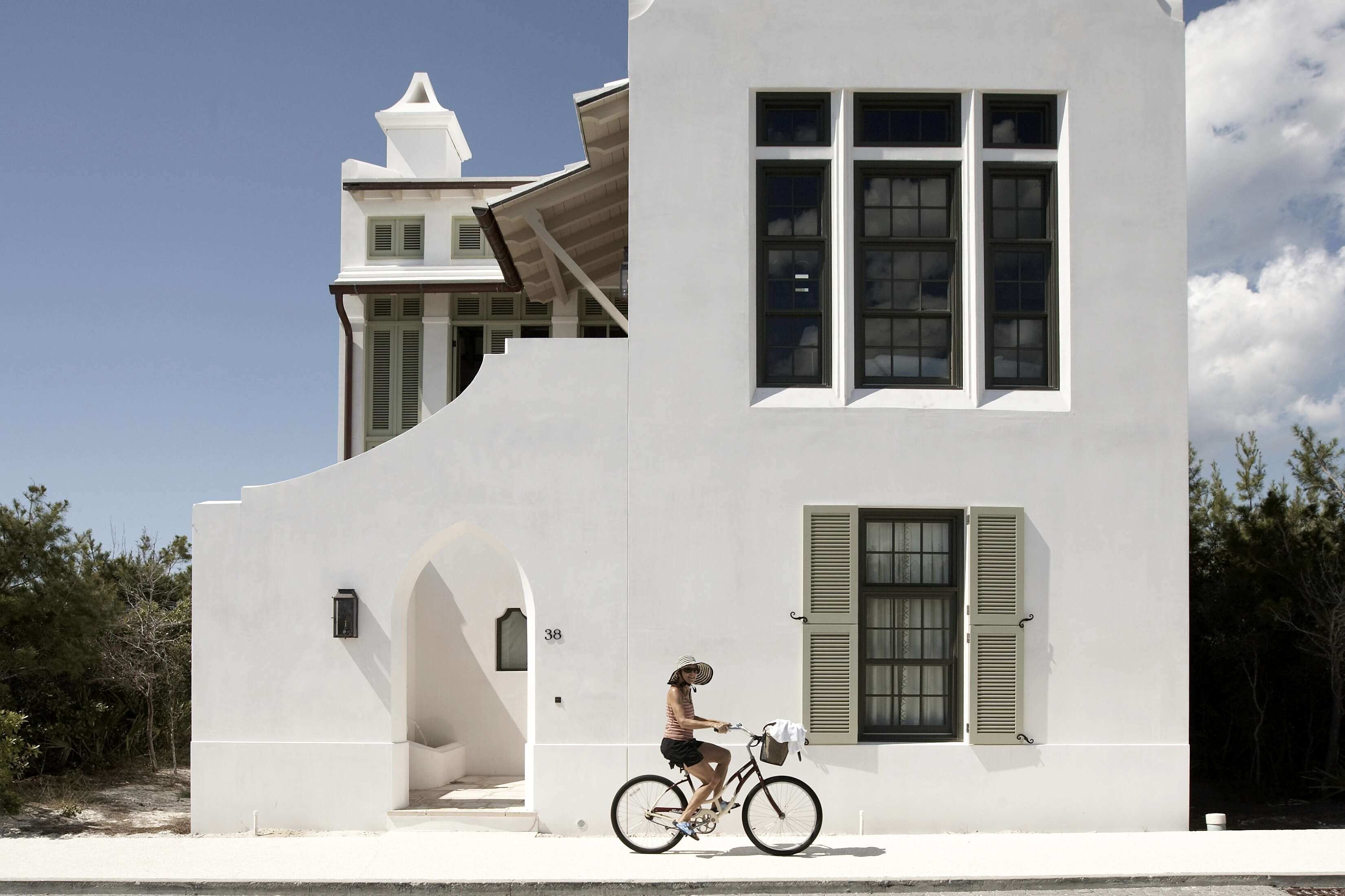 woman biking in front of white building